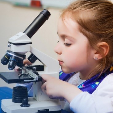 A child is using a microscope to look at a lab slide.
