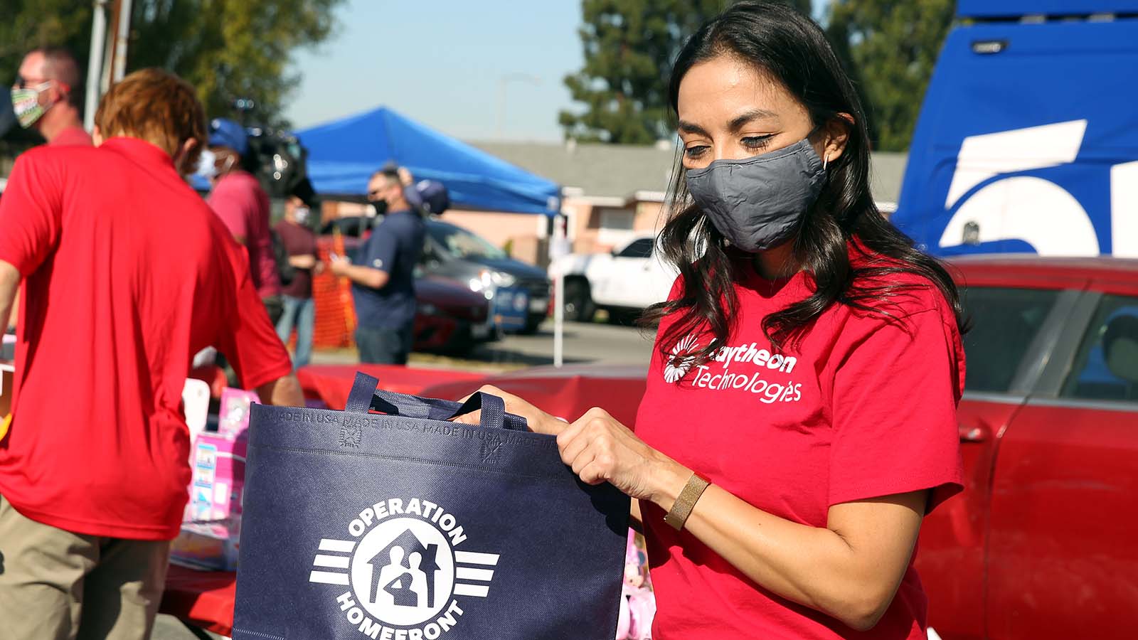 Raytheon Technologies volunteer holding Operation Homefront bag and putting food items in it for military families.