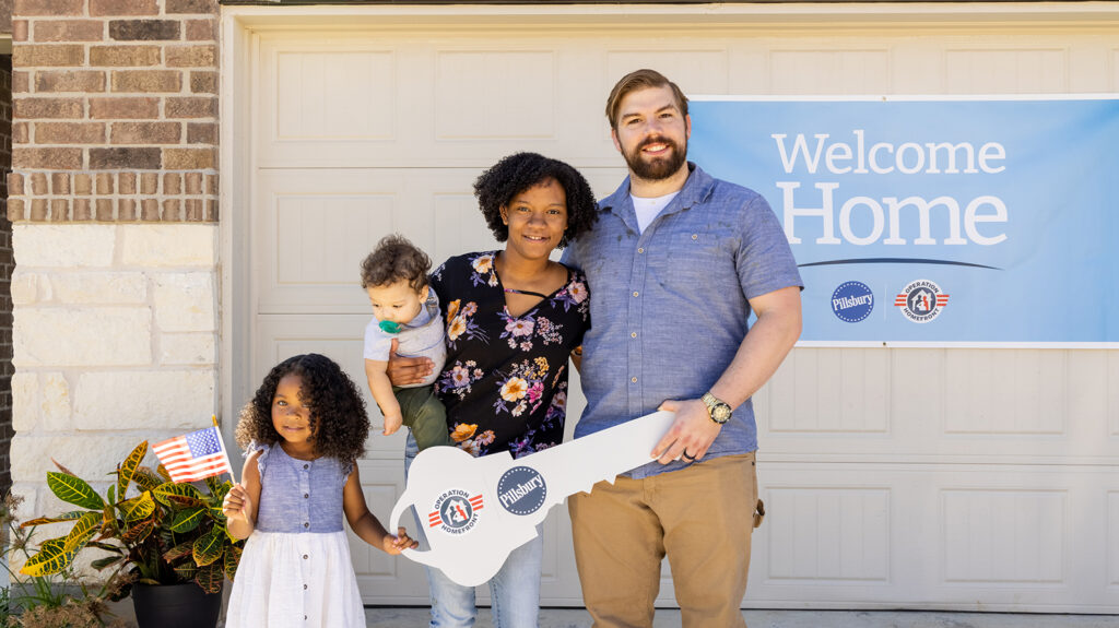 Photo of a family standing in front of a garage door receiving housing assistance