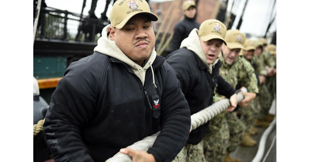 Navy seamen tugging rope on ship.