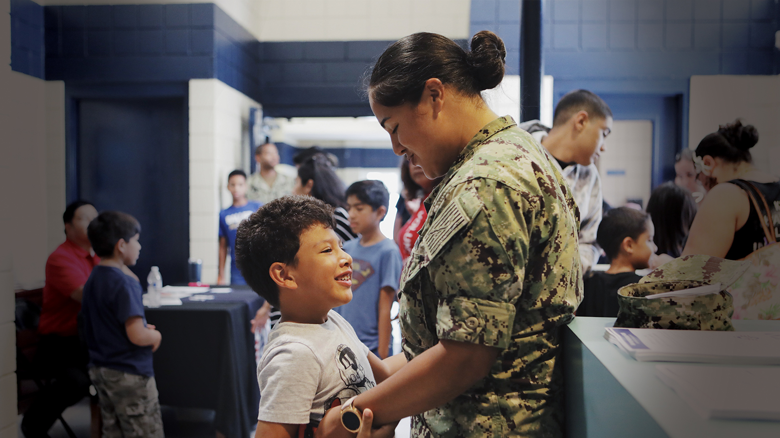Military person holding their child at a school supply event.