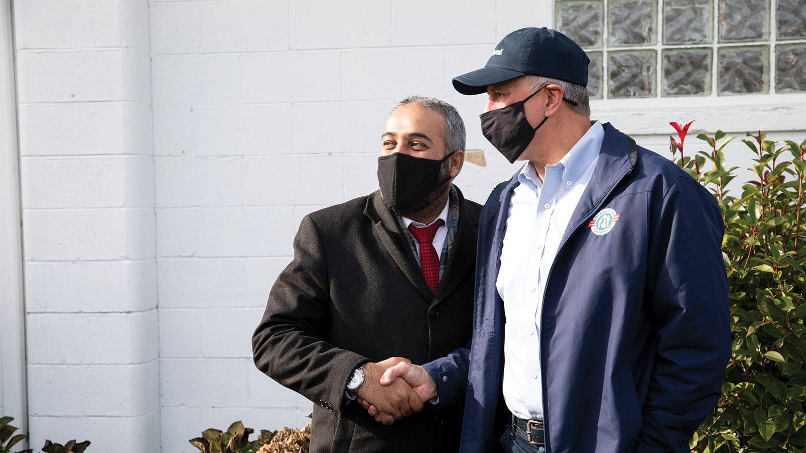 Two masked individuals shaking hands.