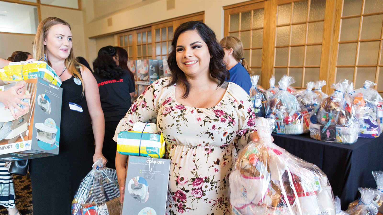 Pregnant person holding baby items at a military baby shower