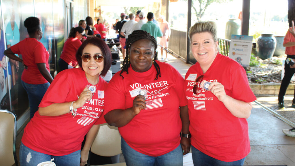 Three volunteers pictured smiling holding buttons.
