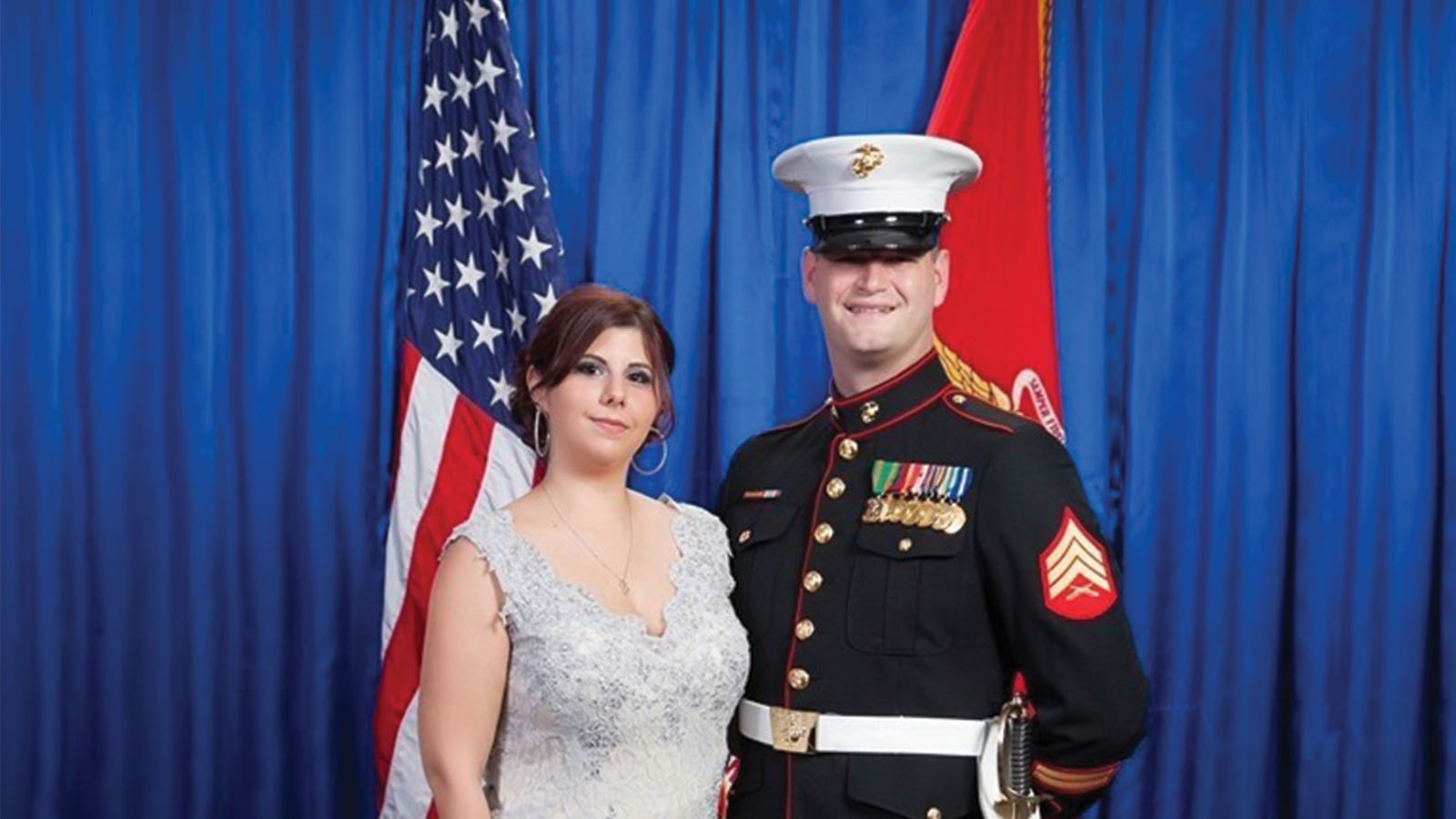 Couple pictured standing in front of two flags.