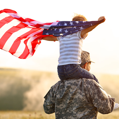 service member holding child with USA flag