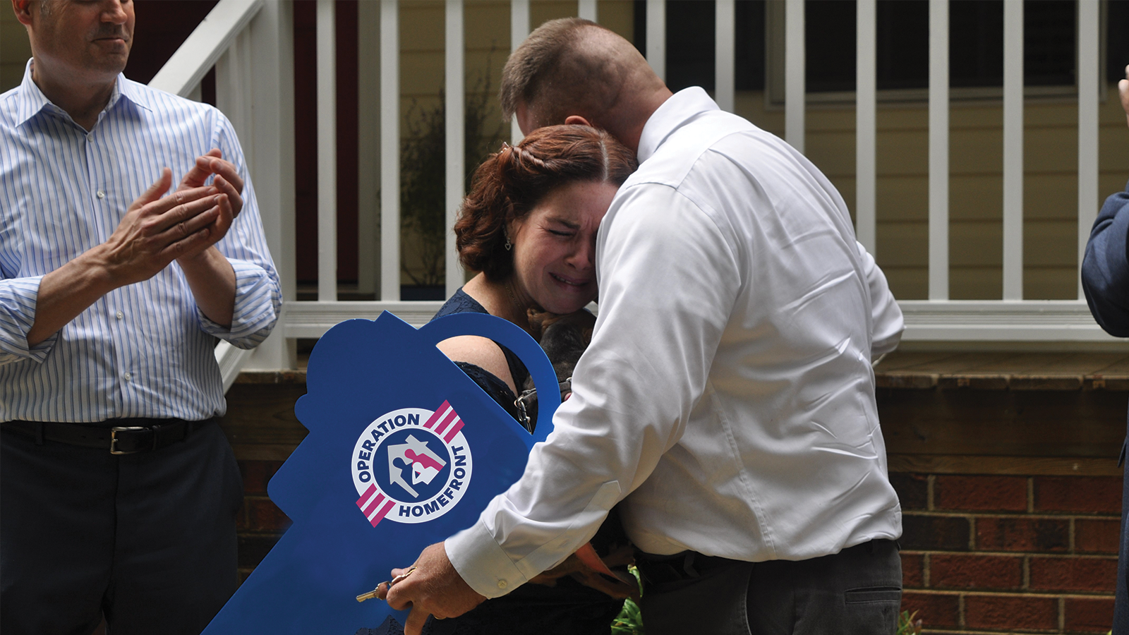 Military family hugging and crying in front of home