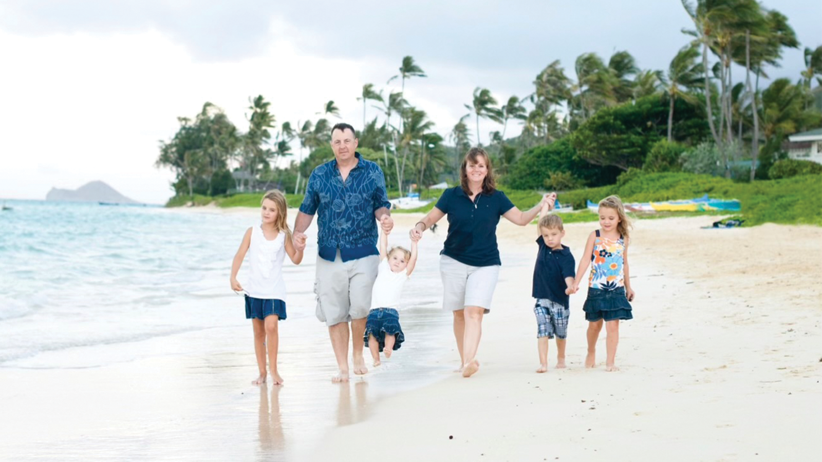 Family smiling and holding hands on a beach