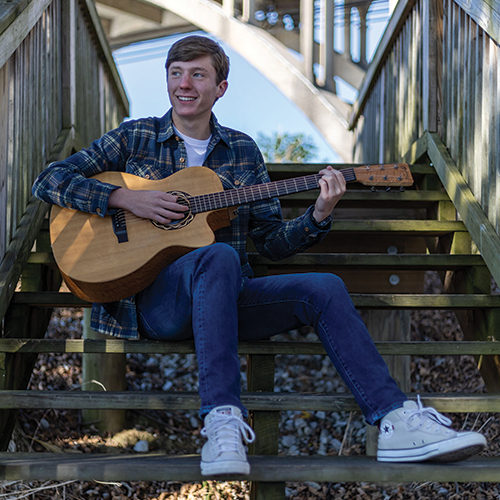 boy sitting on stoop with guitar