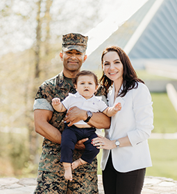 Marine veteran, his wife, and child hugging and smiling.
