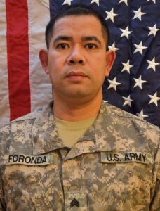 Army Veteran Noli Foronda standing in front of American Flag for a service picture.