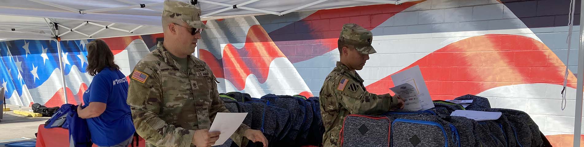 Two male service members counting backpacks outside