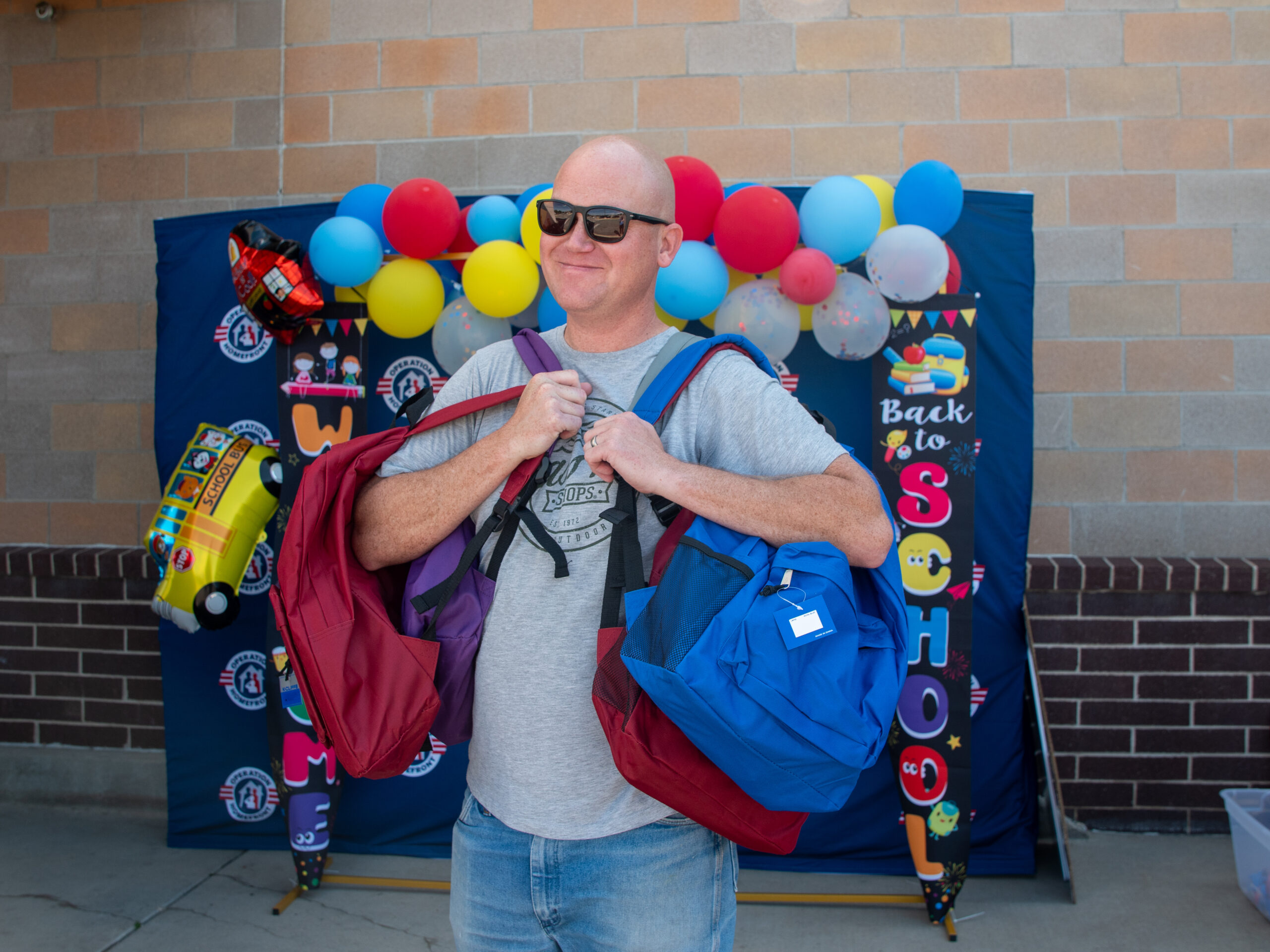 dad holding four backpacks for all of his children