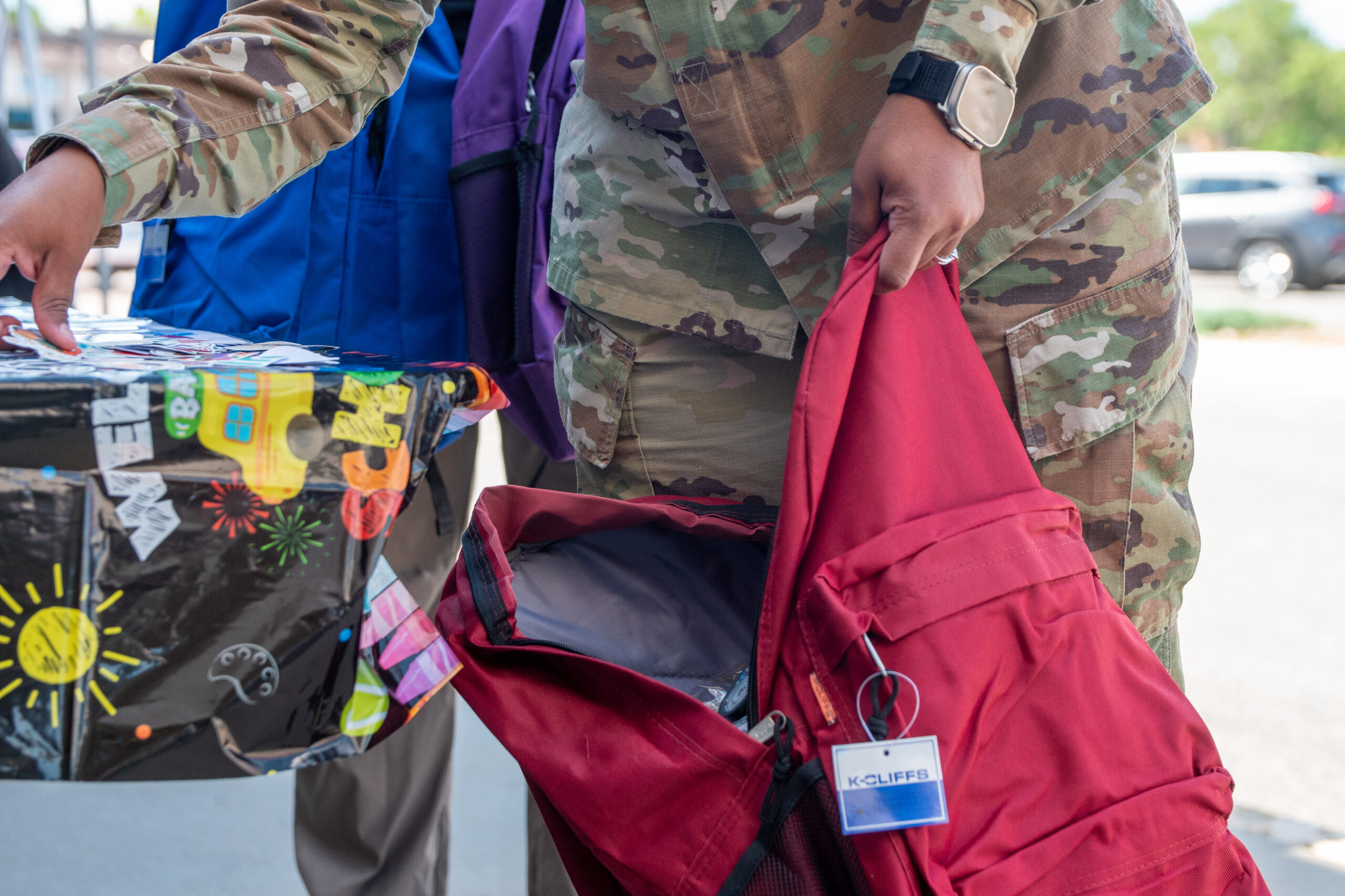 veteran in uniform holding a red backpack