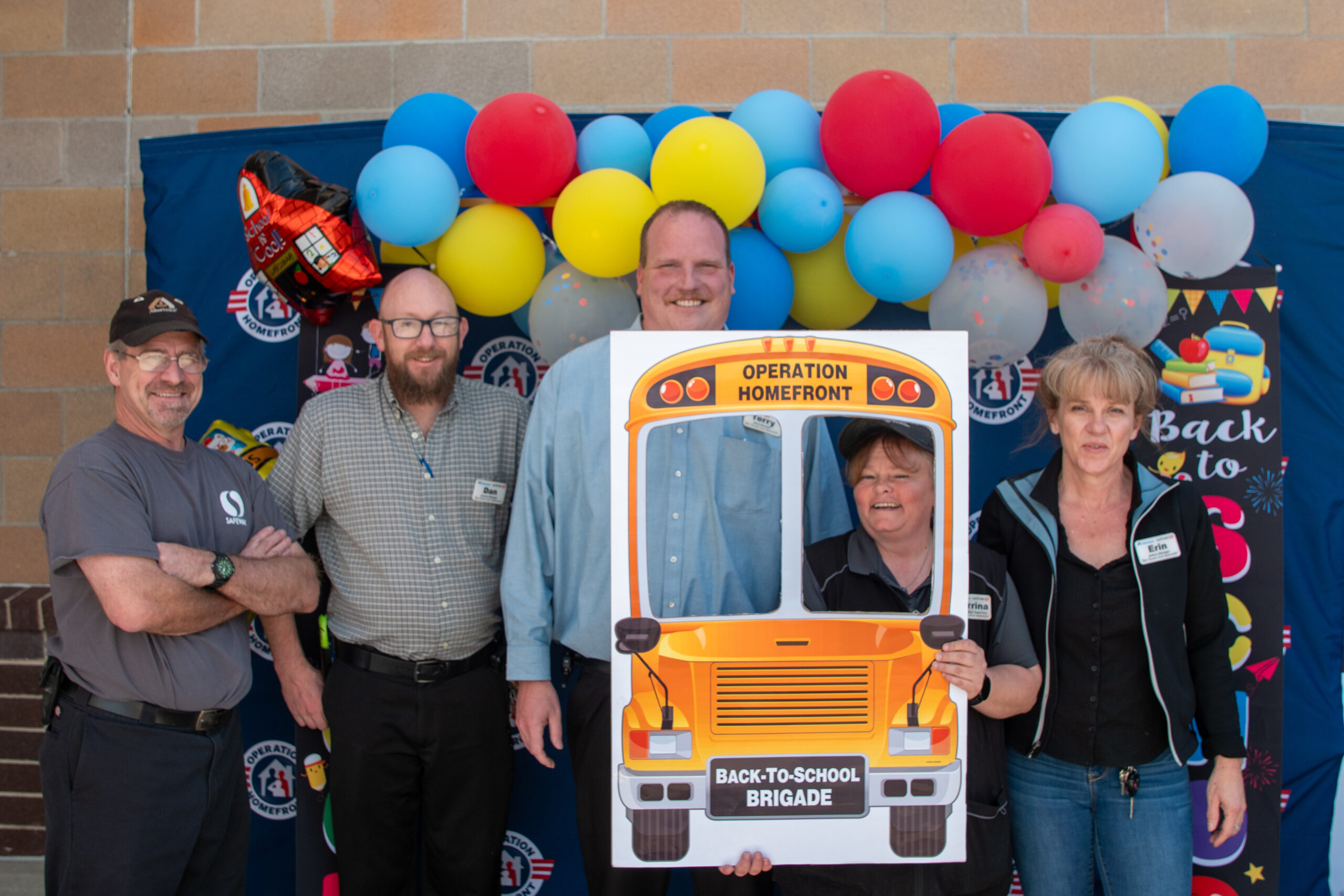 group of people holding a school bus operation homefront sign
