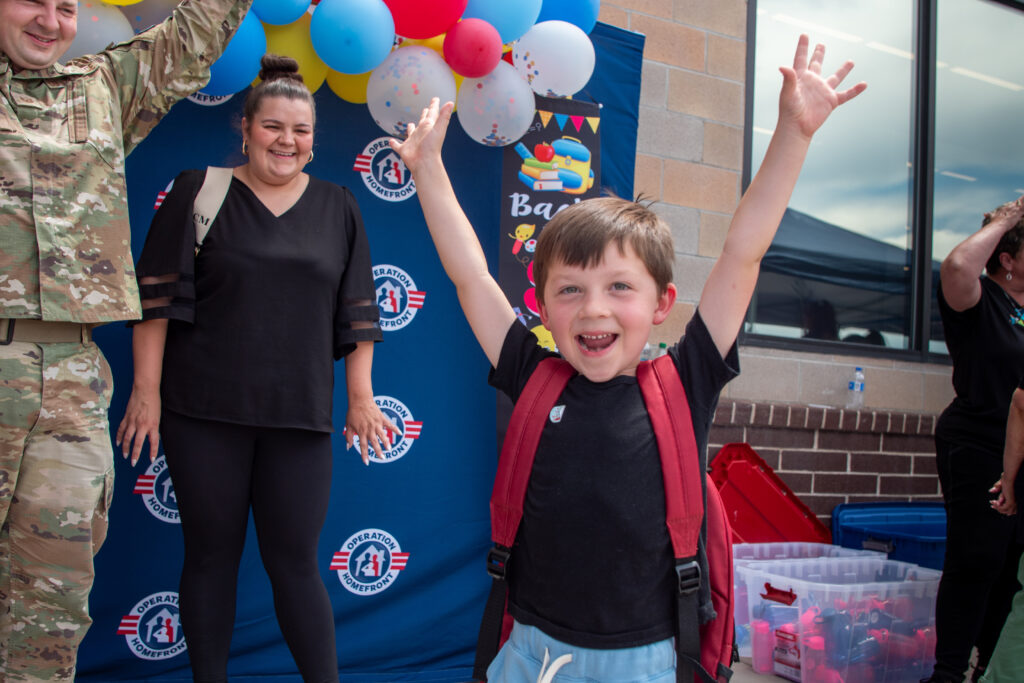 boy with arms in the air in front of his mom and dad