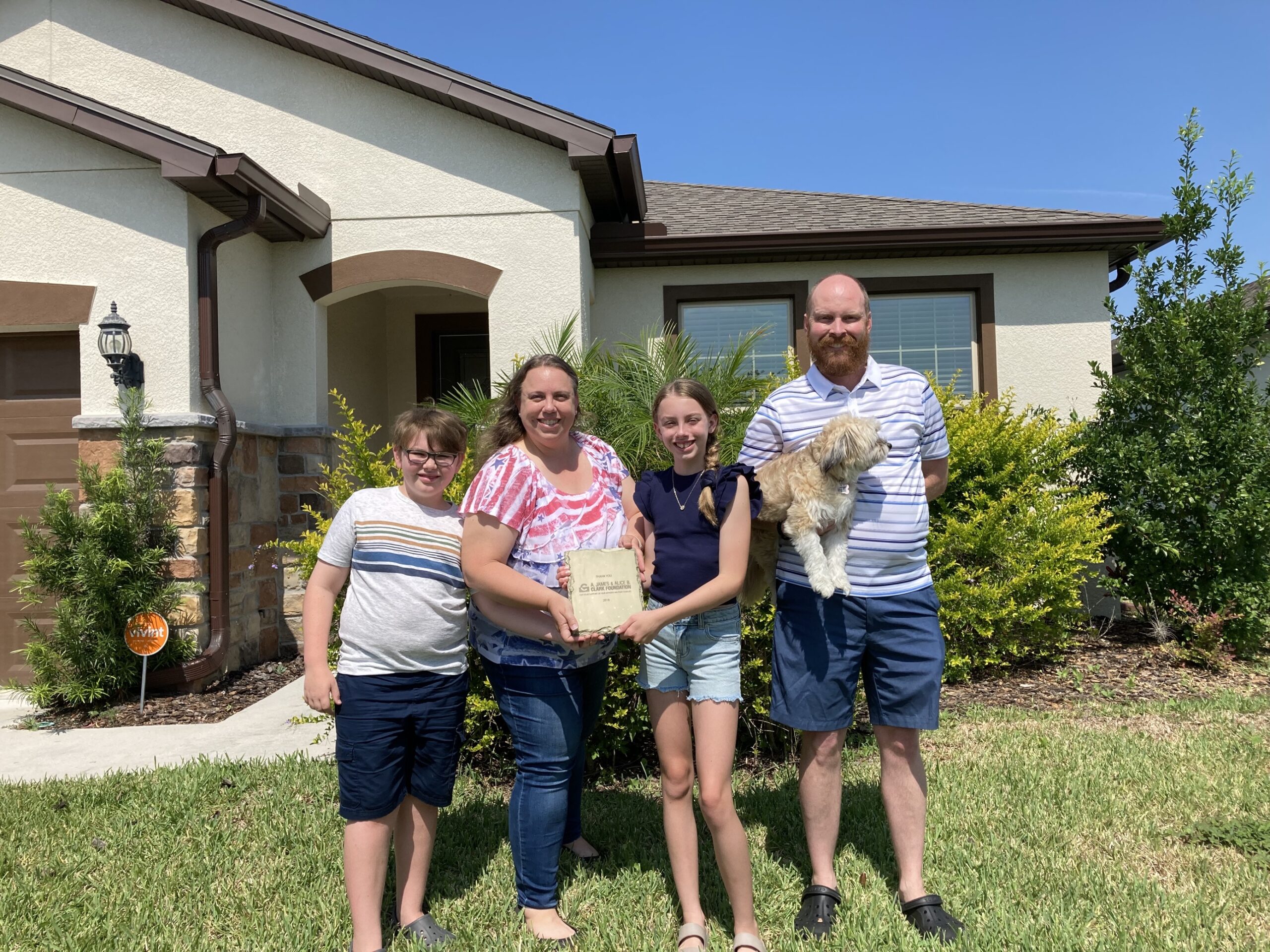 family of four standing in front of home