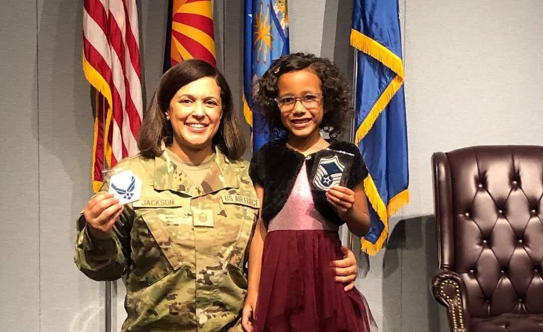 mom and daughter smiling in front of flags