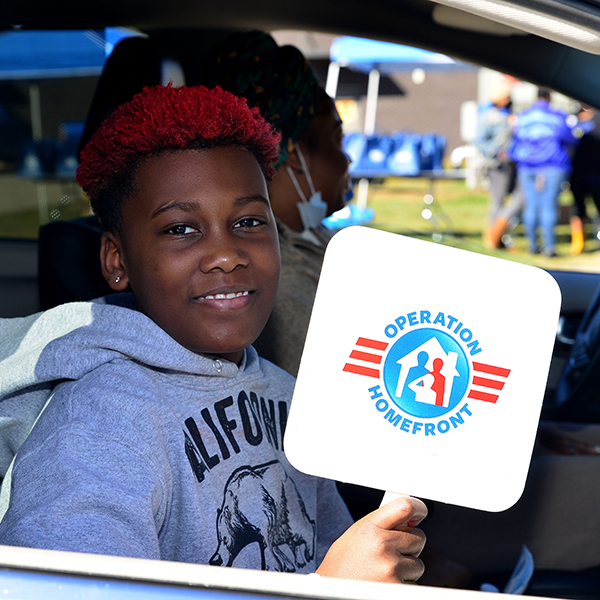 Child in car holding an Operation Homefront sign