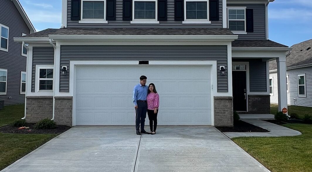 husband and wife in front of their new home