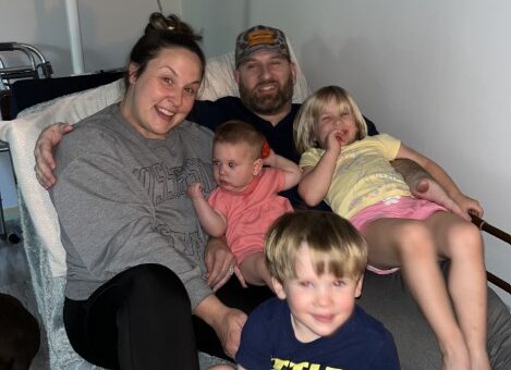 husband, wife, and three children laying in hospital bed together